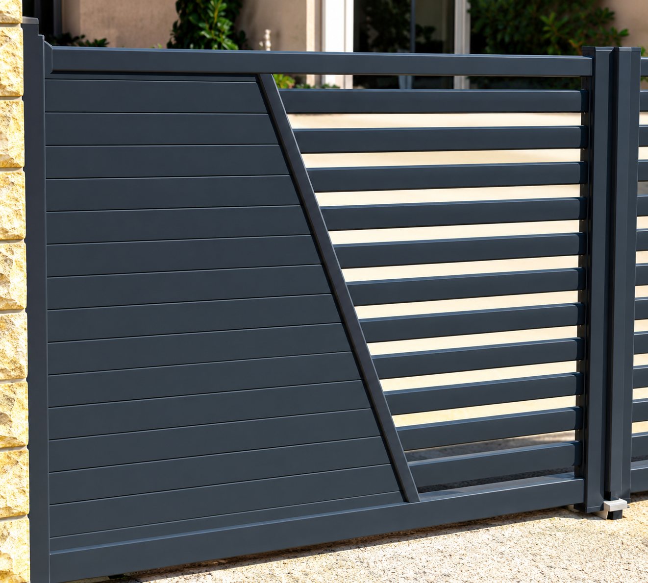 Portail moderne gris anthracite composé d'un panneau plein et de lames horizontales ajourées, installé entre deux piliers.