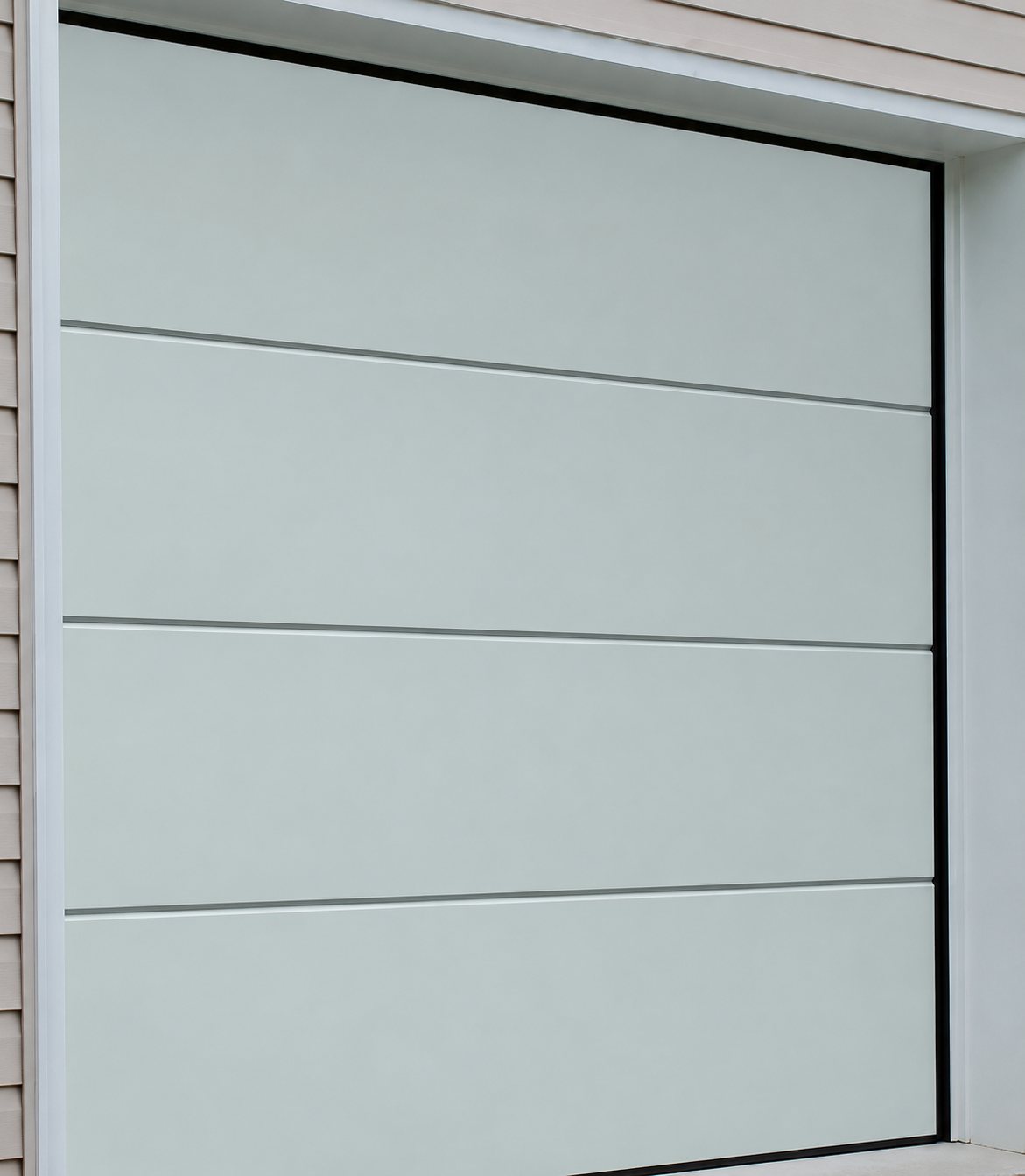 Une porte de garage sectionnelle gris clair à panneaux horizontaux, encadrée d'un bardage clair sur la façade d'une maison.